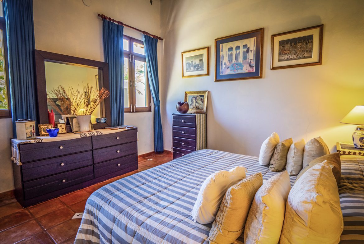 buyDRproperty Cozy bedroom with blue curtains, striped bedding, and wall art Sosua Real Estate