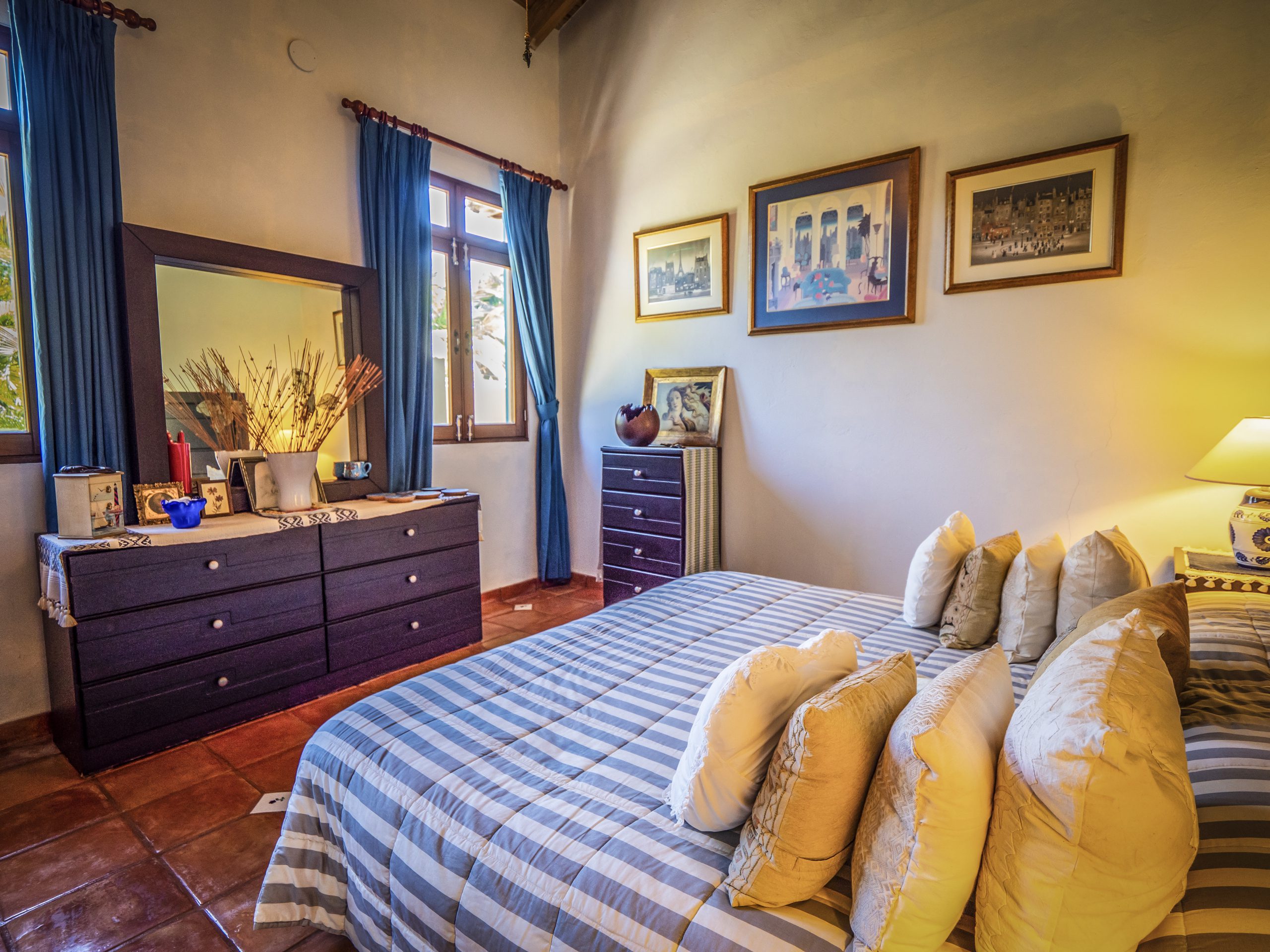 buyDRproperty Cozy bedroom with blue curtains, striped bedding, and wall art Sosua Real Estate