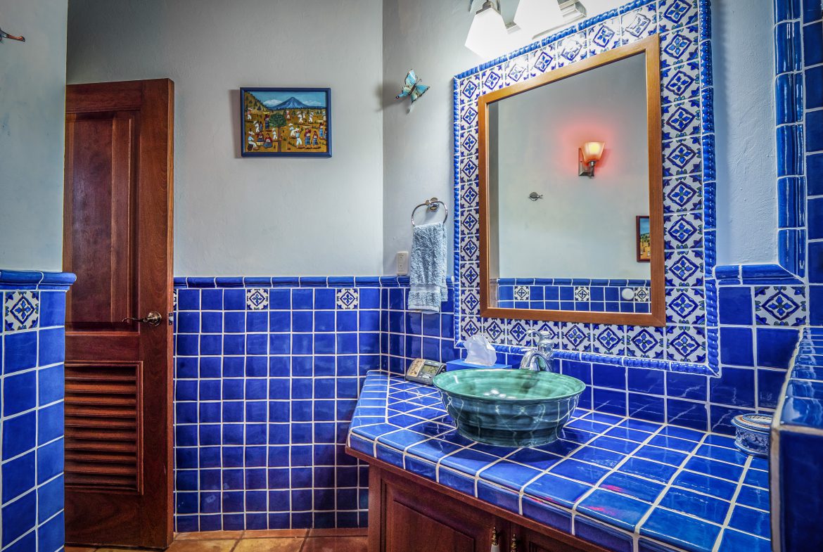 buyDRproperty Blue-tiled bathroom with decorative mirror and green sink Sosua Real Estate