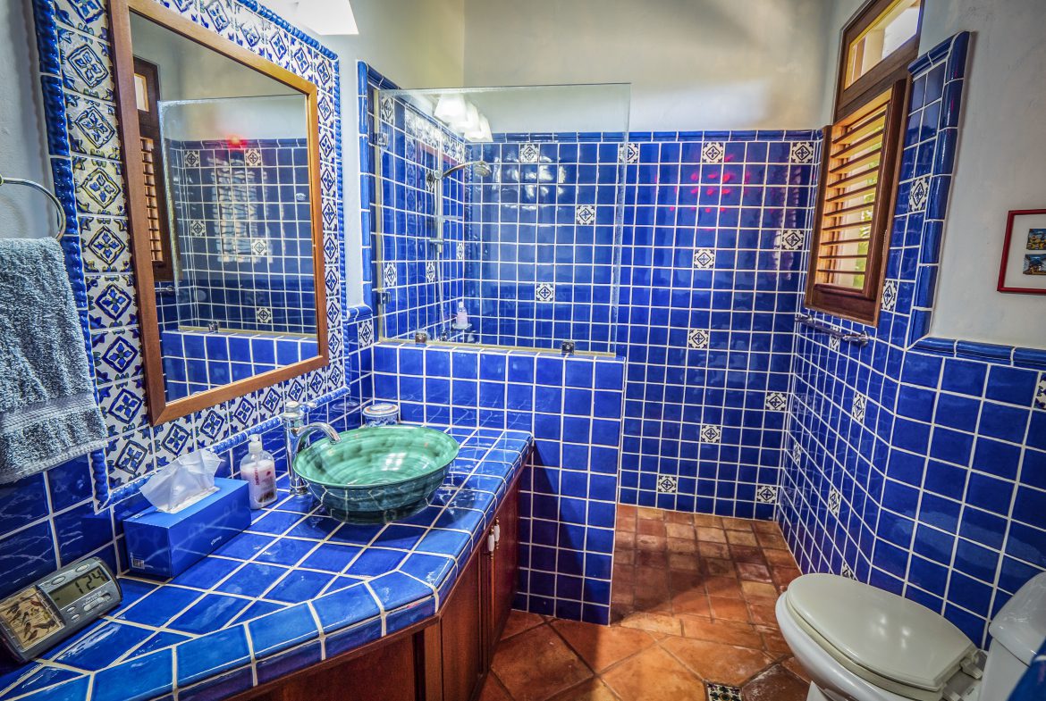 buyDRproperty Blue tiled bathroom with a glass sink and wooden accents Sosua Real Estate