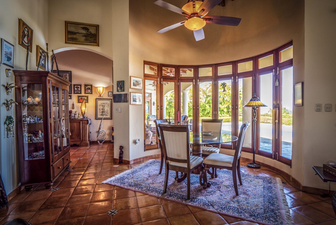 buyDRproperty Cozy dining room with tall windows, wooden furniture, and ceiling fan Sosua Real Estate
