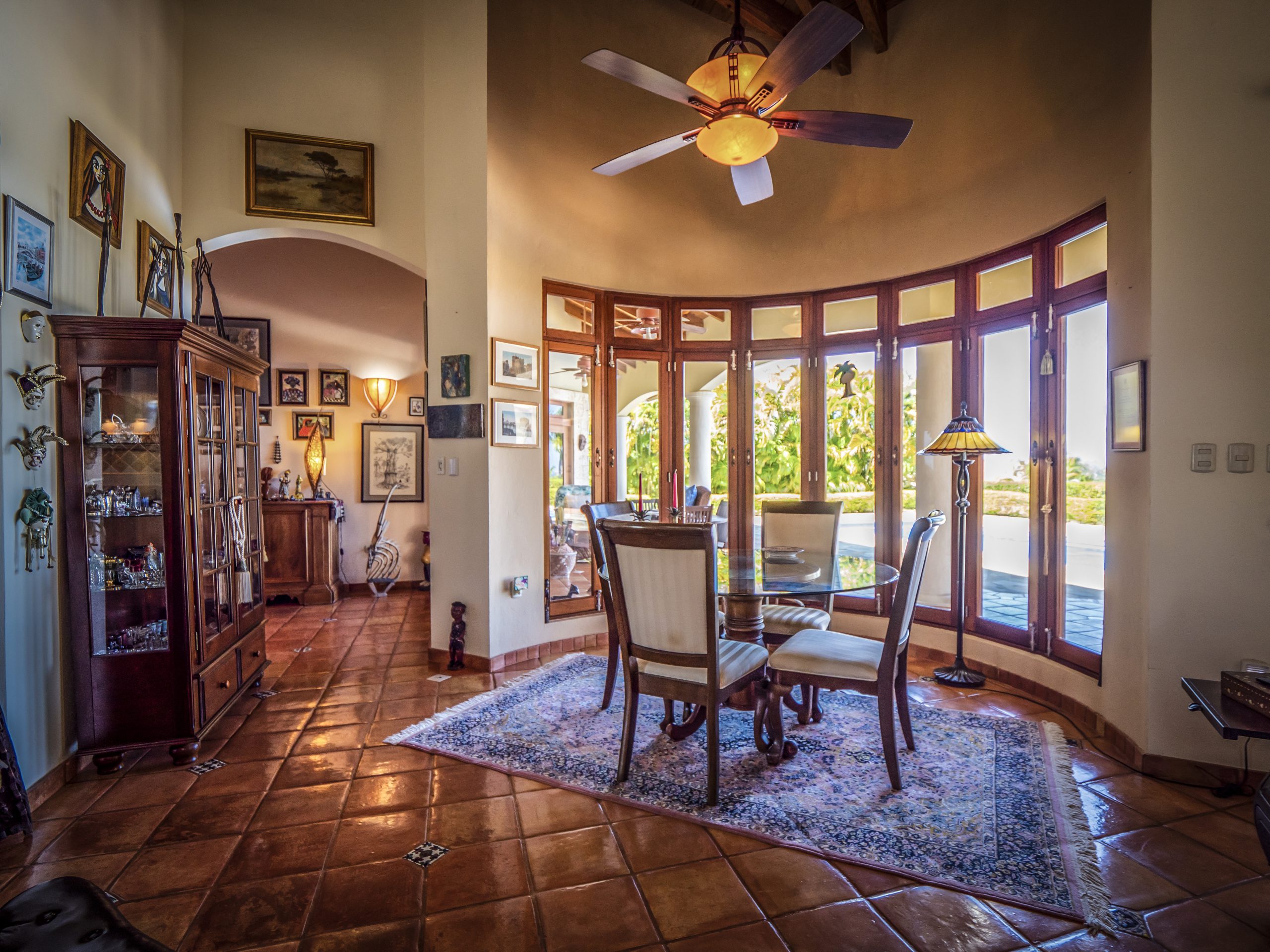 buyDRproperty Cozy dining room with tall windows, wooden furniture, and ceiling fan Sosua Real Estate