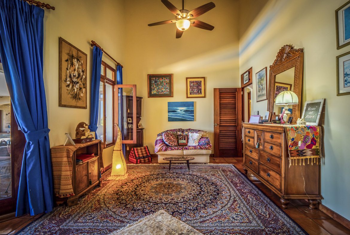 buyDRproperty Cozy living room with blue curtains, ornate rug, and ceiling fan Sosua Real Estate