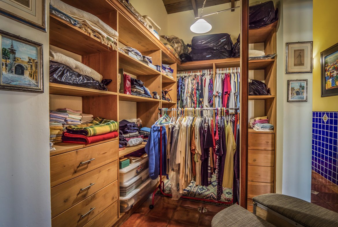 buyDRproperty Organized walk-in closet with clothes on hangers and folded linens Sosua Real Estate