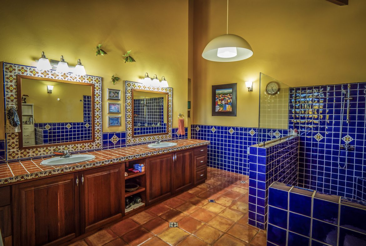 buyDRproperty Rustic bathroom with blue tiles and wooden cabinets under warm lighting Sosua Real Estate