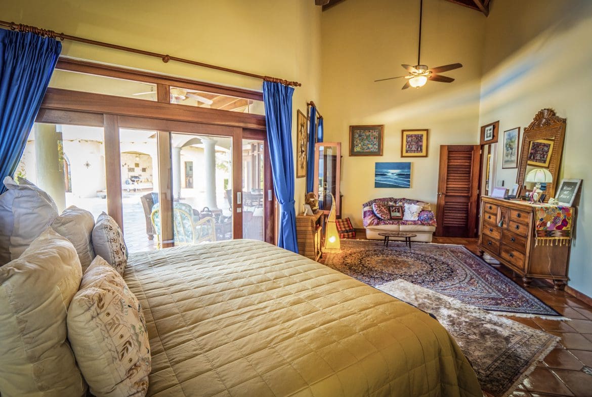 buyDRproperty Spacious bedroom with a cozy bed, blue curtains, and a view of the patio Sosua Real Estate