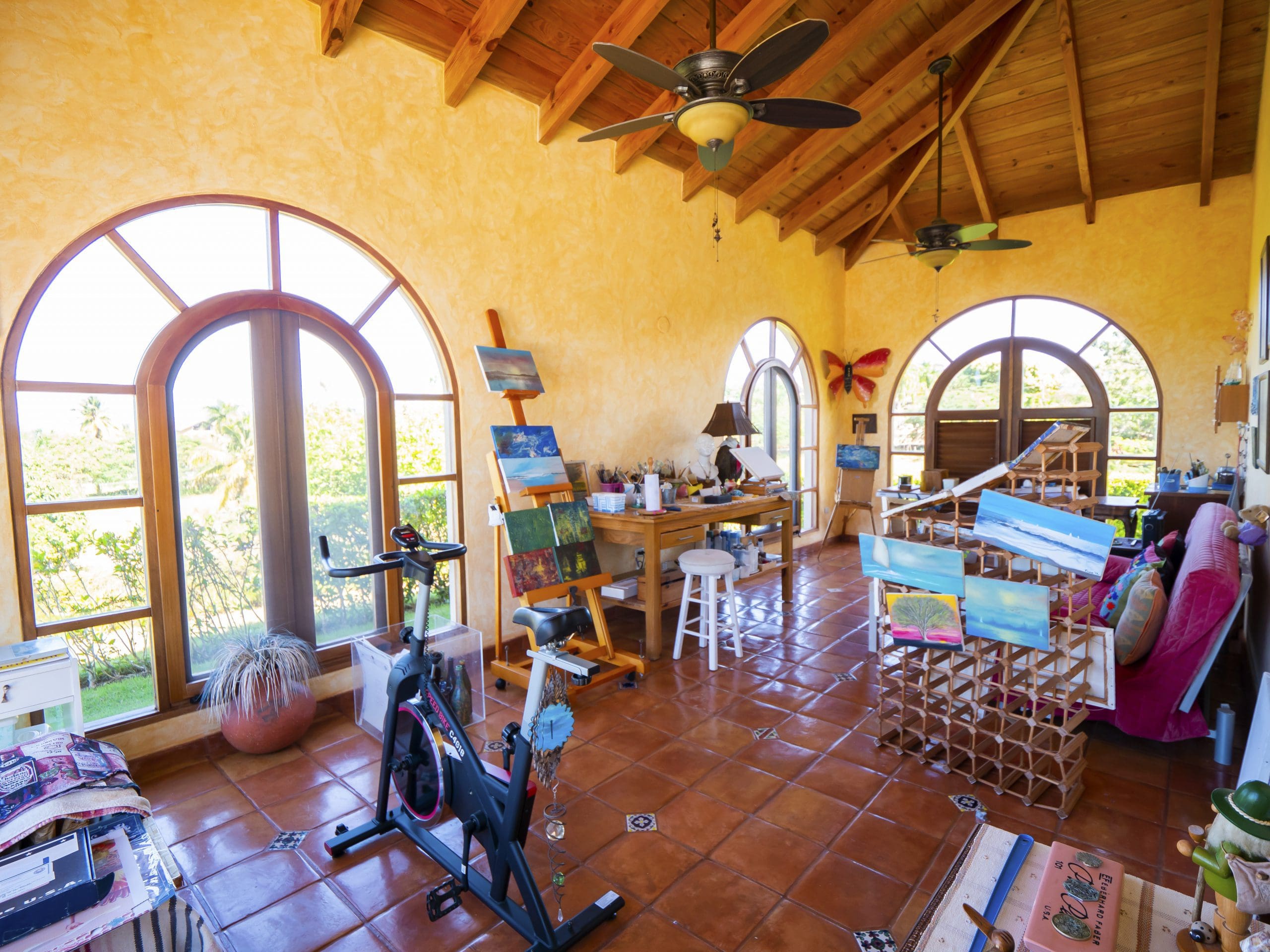 buyDRproperty Bright art studio with easels, exercise bike, and large arched windows Sosua Real Estate