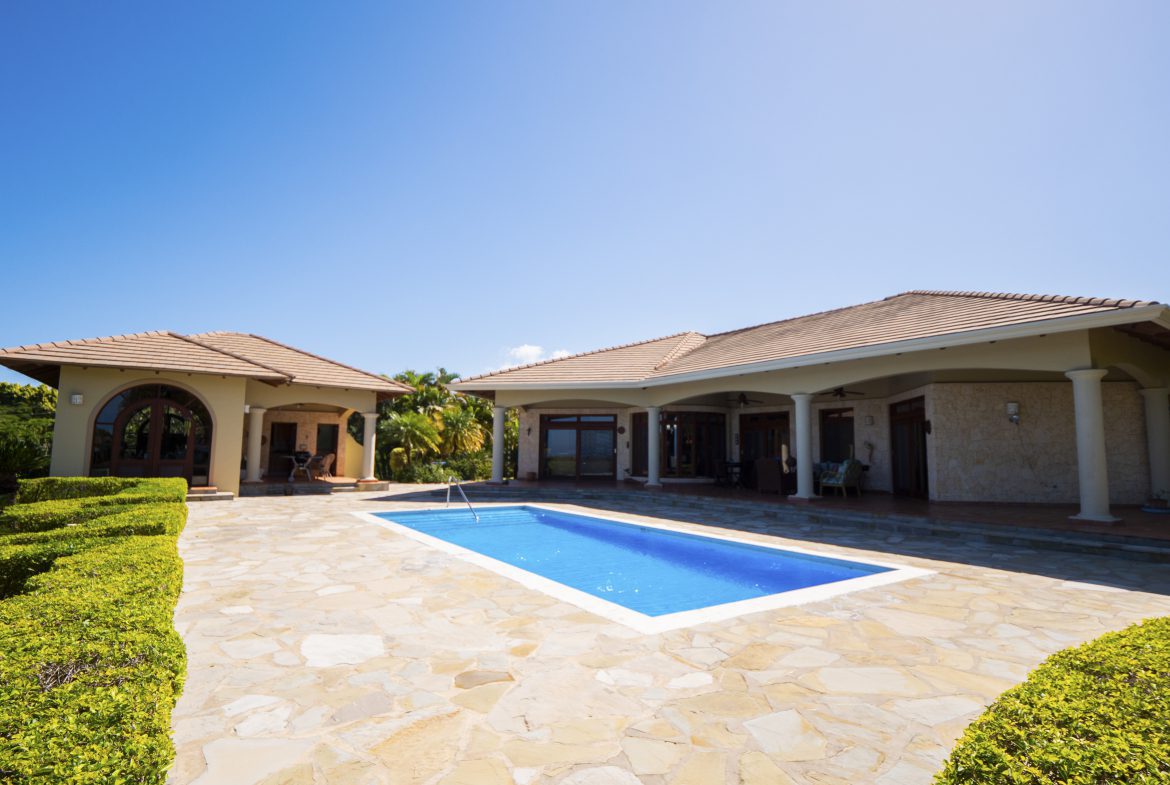 buyDRproperty Spacious villa with a blue swimming pool under a clear sky Sosua Real Estate