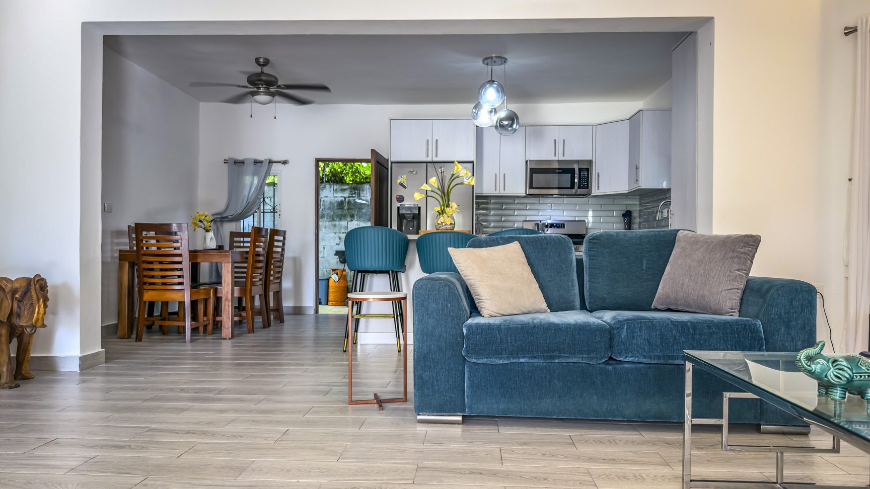 buyDRproperty Modern open-plan living room and kitchen with blue sofa and wooden dining set Sosua Real Estate