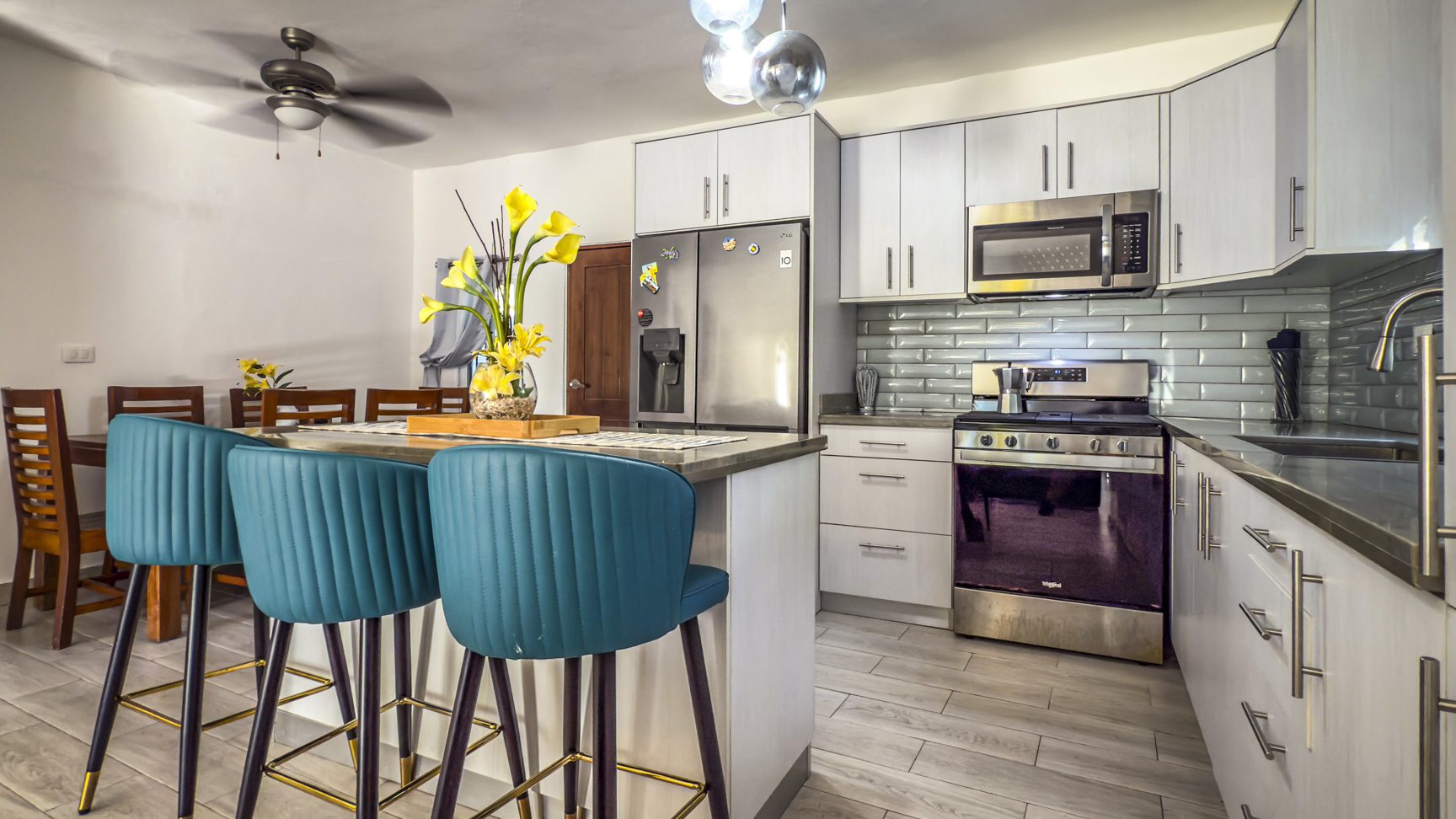 buyDRproperty Modern kitchen with blue bar stools, stainless steel appliances, and white cabinets. Sosua Real Estate
