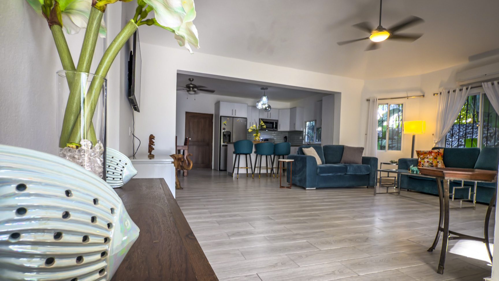 buyDRproperty Bright, open-plan living room with teal sofas and modern decor. Sosua Real Estate