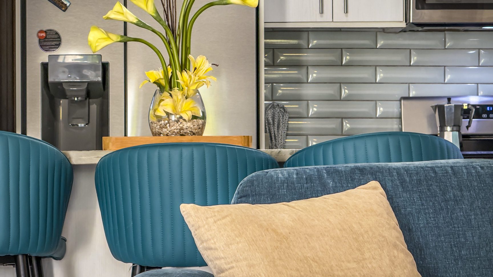buyDRproperty Teal bar stools at a kitchen counter with yellow flowers in a glass vase. Sosua Real Estate
