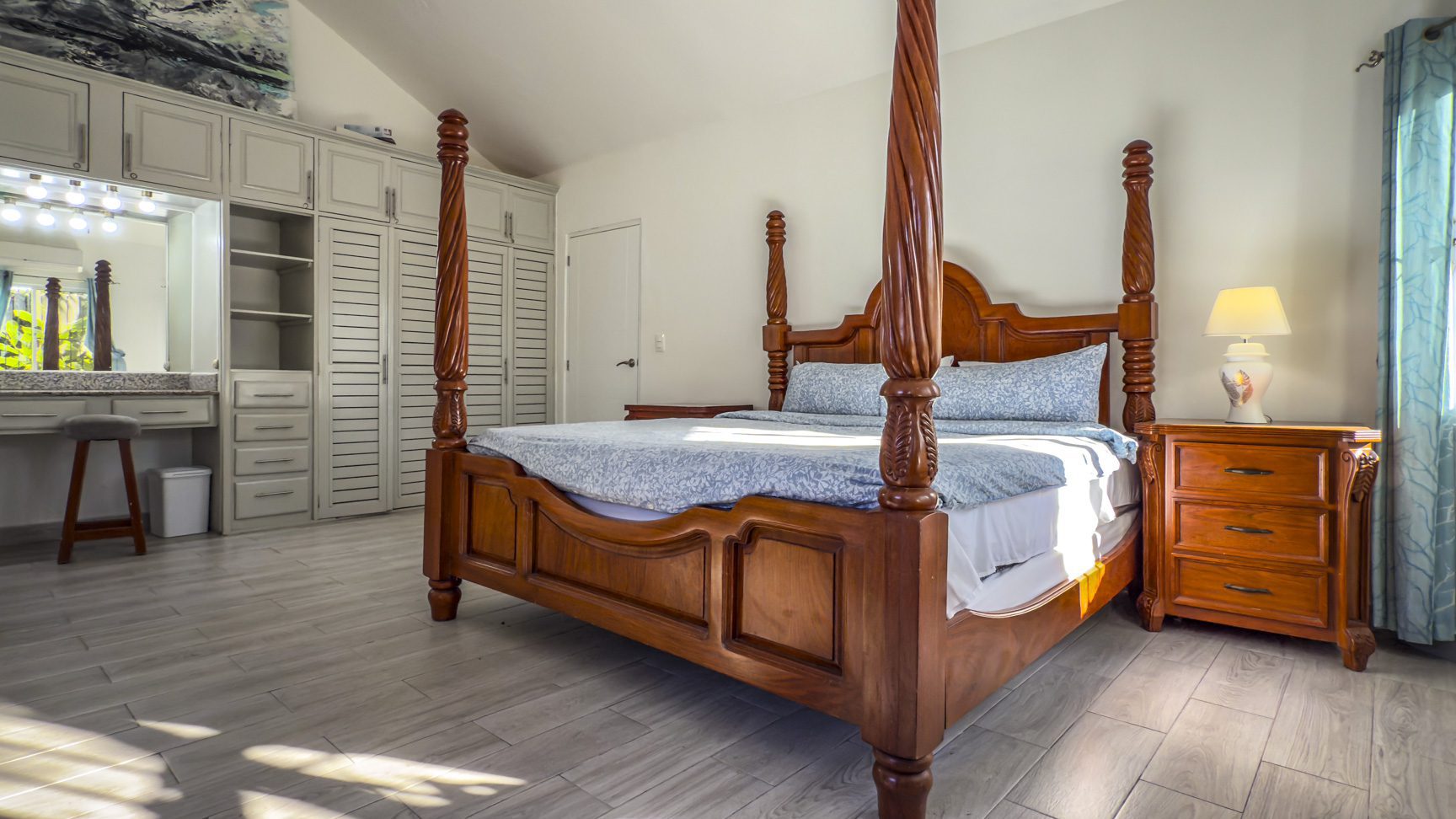 buyDRproperty Bedroom with a wooden four-poster bed, vanity, and light-colored wood floors Sosua Real Estate