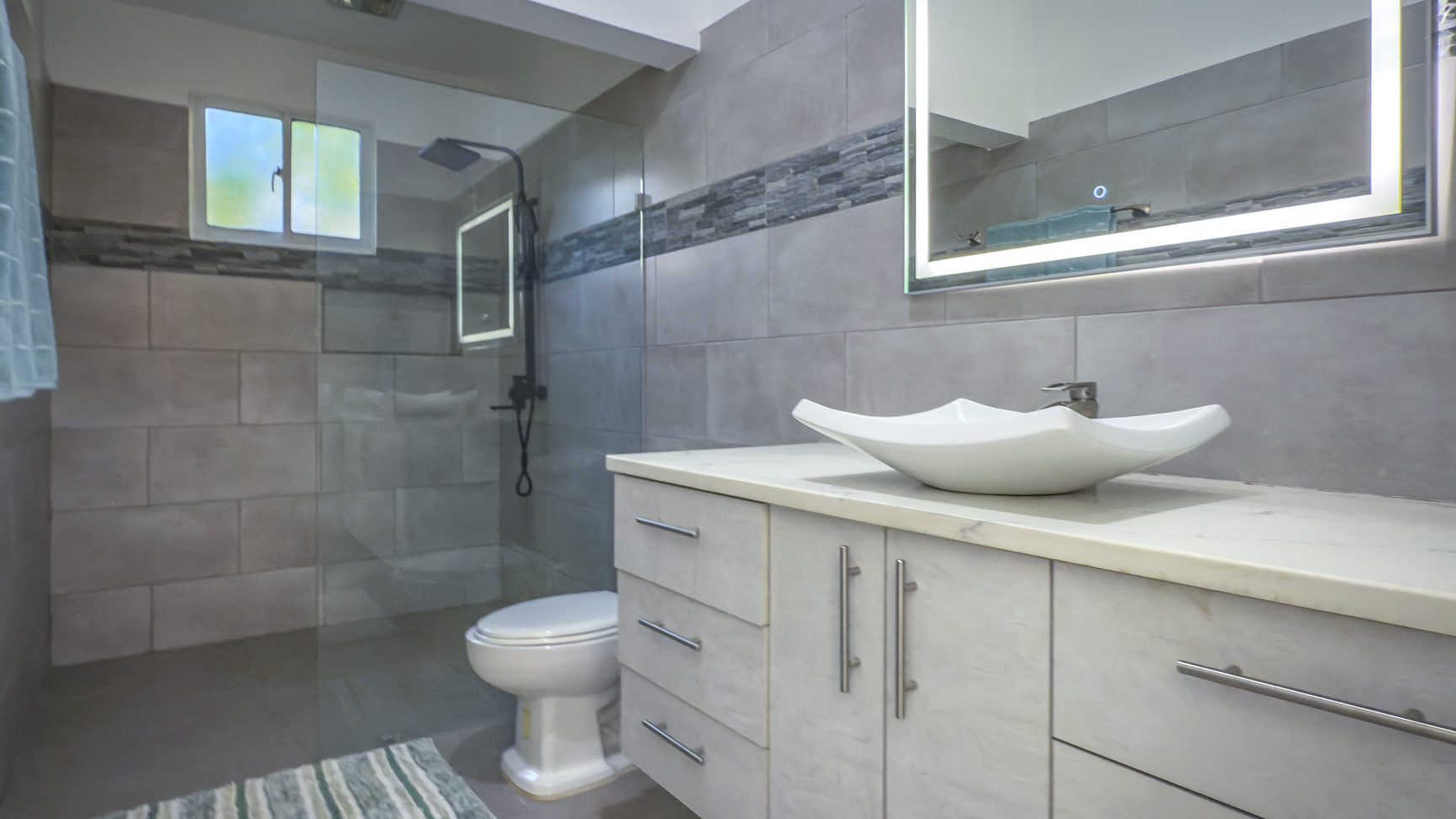 buyDRproperty Modern bathroom with minimalist design, featuring a vessel sink and gray tile shower. Sosua Real Estate