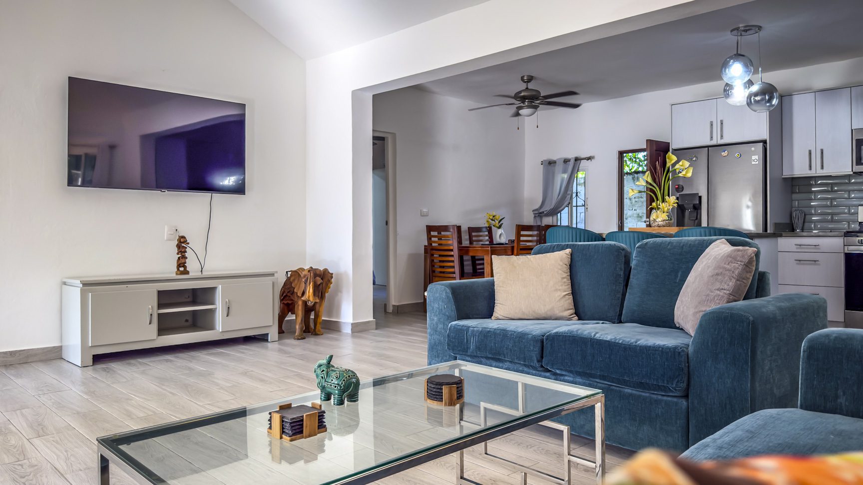 buyDRproperty Bright living room with blue sofa, TV, and open-plan kitchen. Modern interior design. Sosua Real Estate