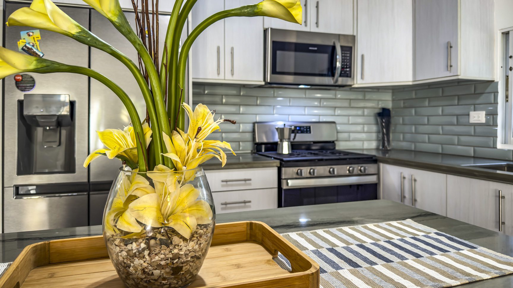 buyDRproperty Modern kitchen interior with stainless steel appliances, light cabinets, and a yellow flower arrangement on the countertop. Sosua Real Estate