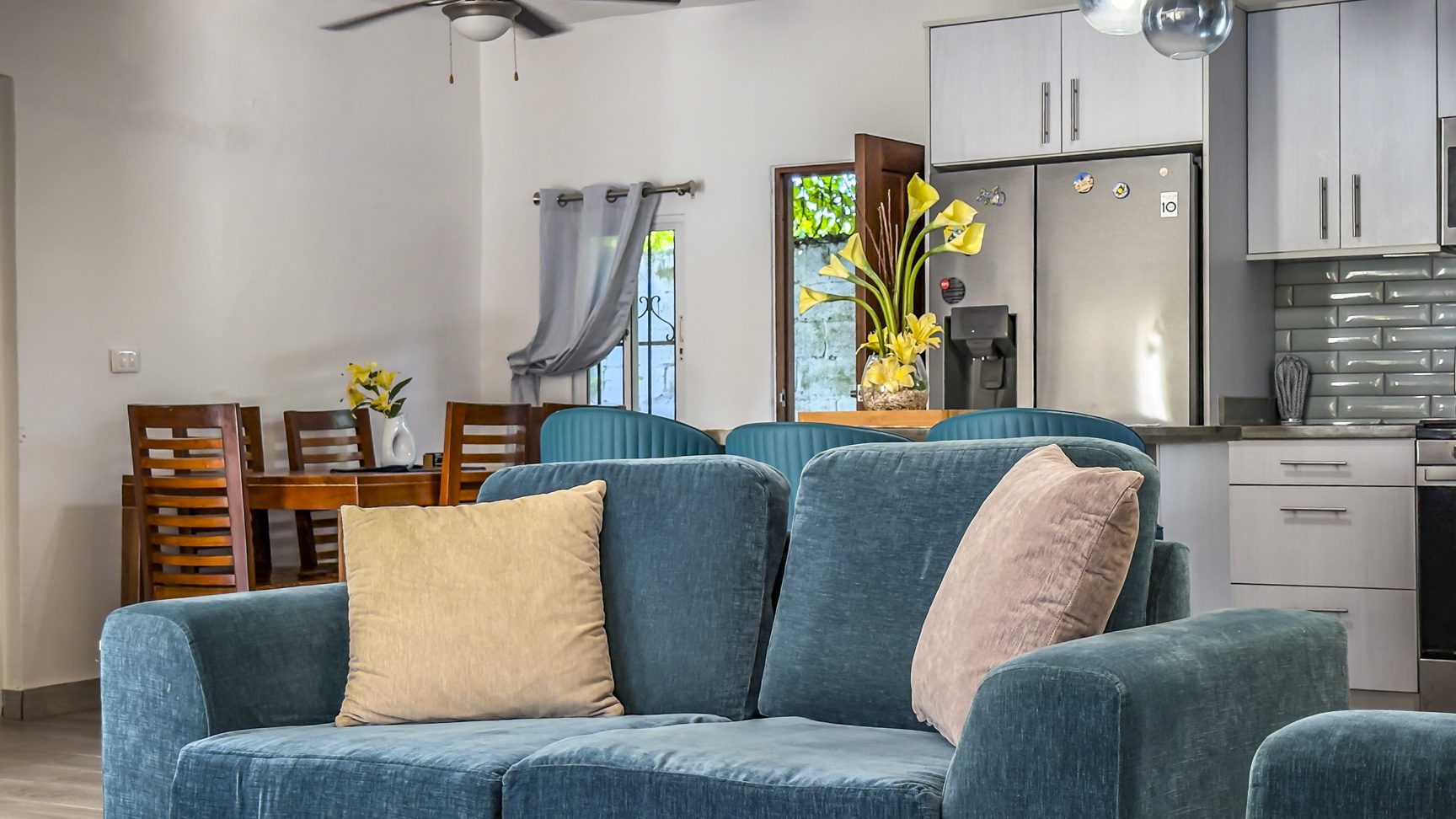 buyDRproperty Living room with blue sofa, open to dining area and kitchen. Modern interior design. Sosua Real Estate