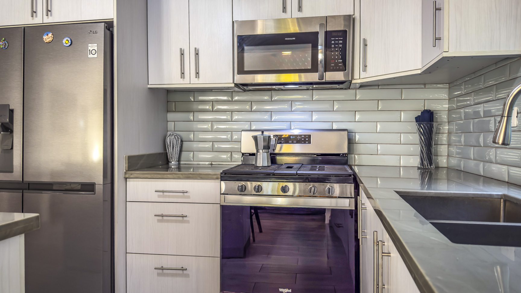 buyDRproperty Modern kitchen with stainless steel appliances and light green tile backsplash Sosua Real Estate