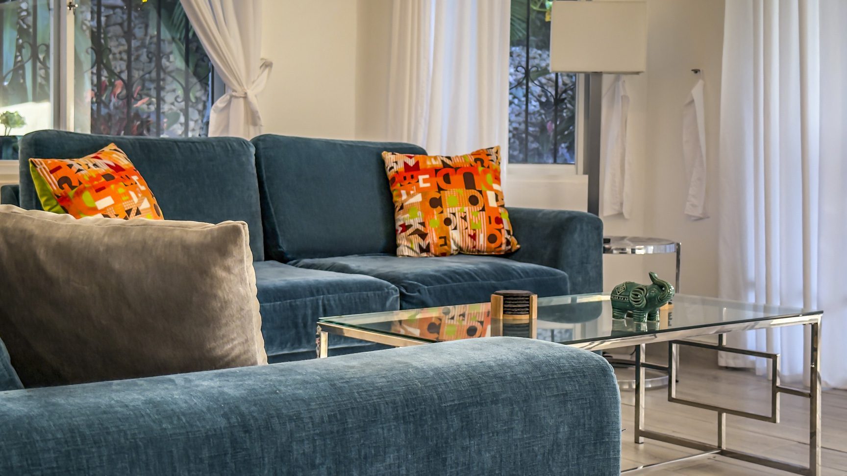 buyDRproperty Blue velvet sofa with colorful pillows and glass coffee table. Sosua Real Estate