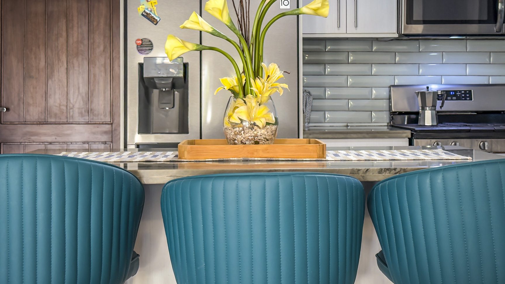 buyDRproperty Kitchen island with blue chairs, yellow calla lilies, stainless steel appliances. Sosua Real Estate
