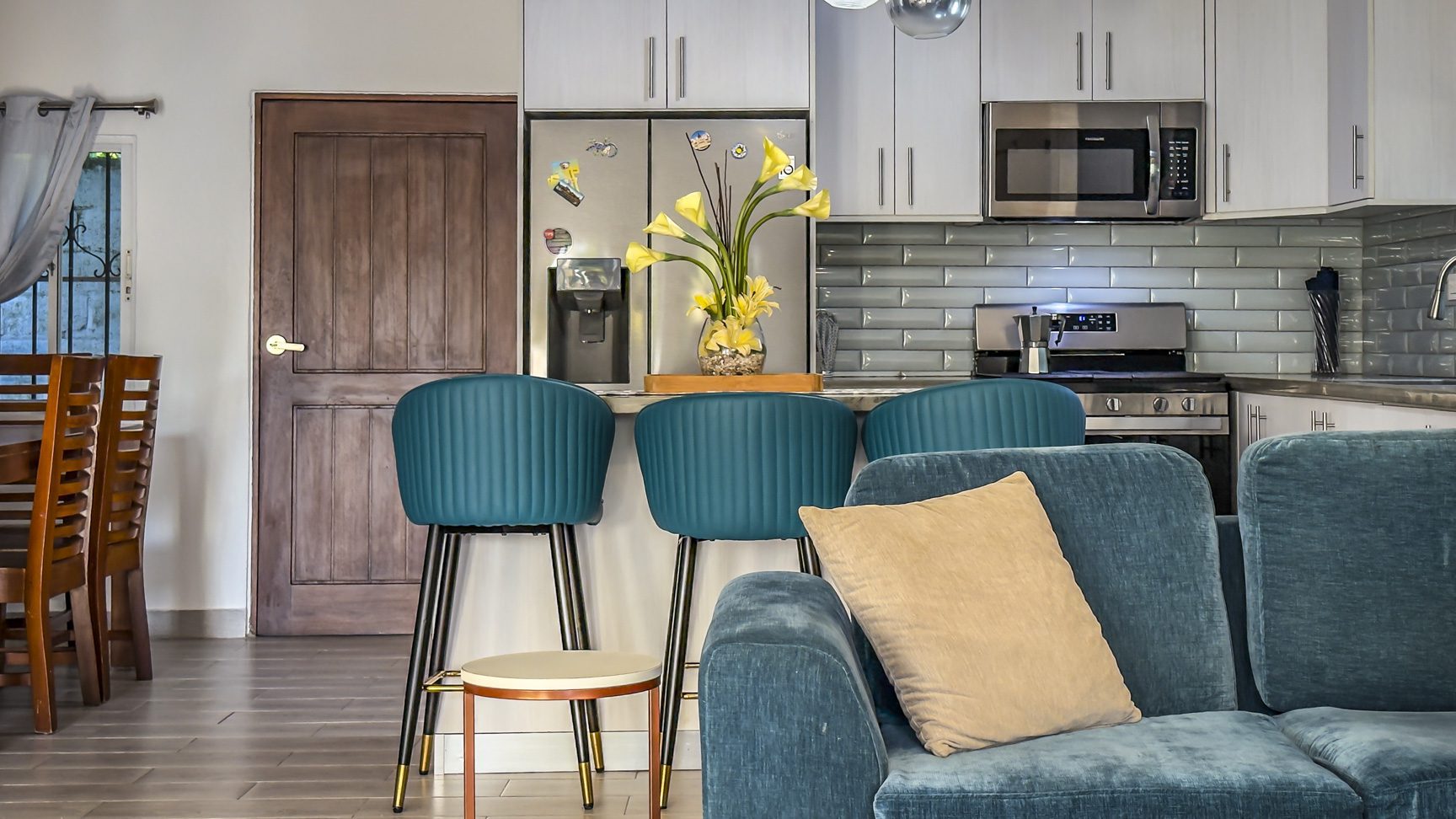 buyDRproperty Modern living room with blue sofa, kitchen, and vase of flowers Sosua Real Estate