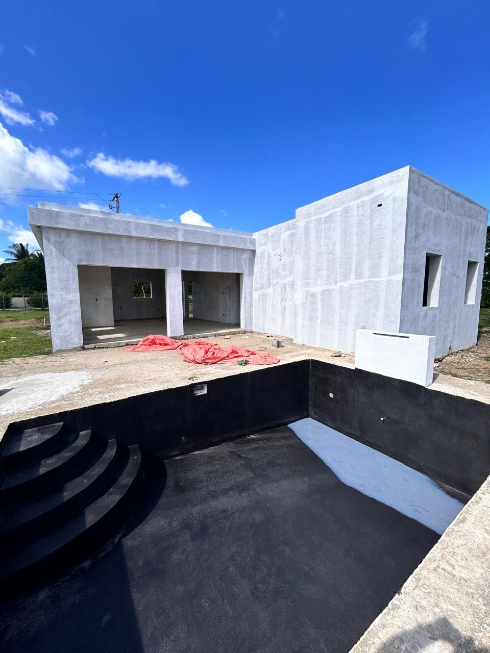 buyDRproperty Unfinished modern house with a black-bottom pool under a blue sky. Sosua Real Estate