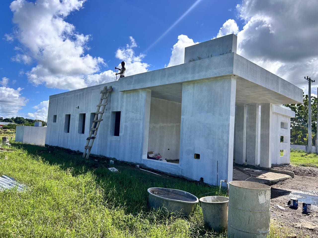 buyDRproperty Unfinished modern house under construction with a worker on the roof and a ladder. Sosua Real Estate