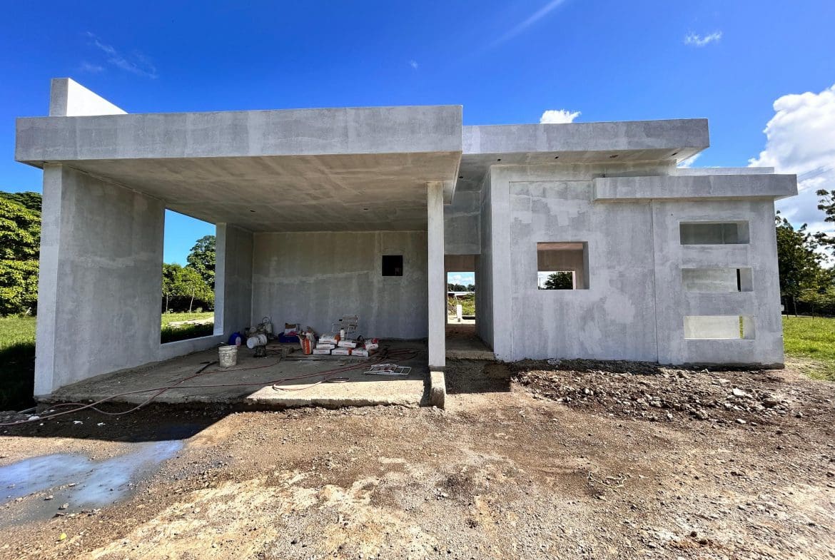 buyDRproperty Unfinished modern house construction with concrete walls and window openings under a bright blue sky. Sosua Real Estate