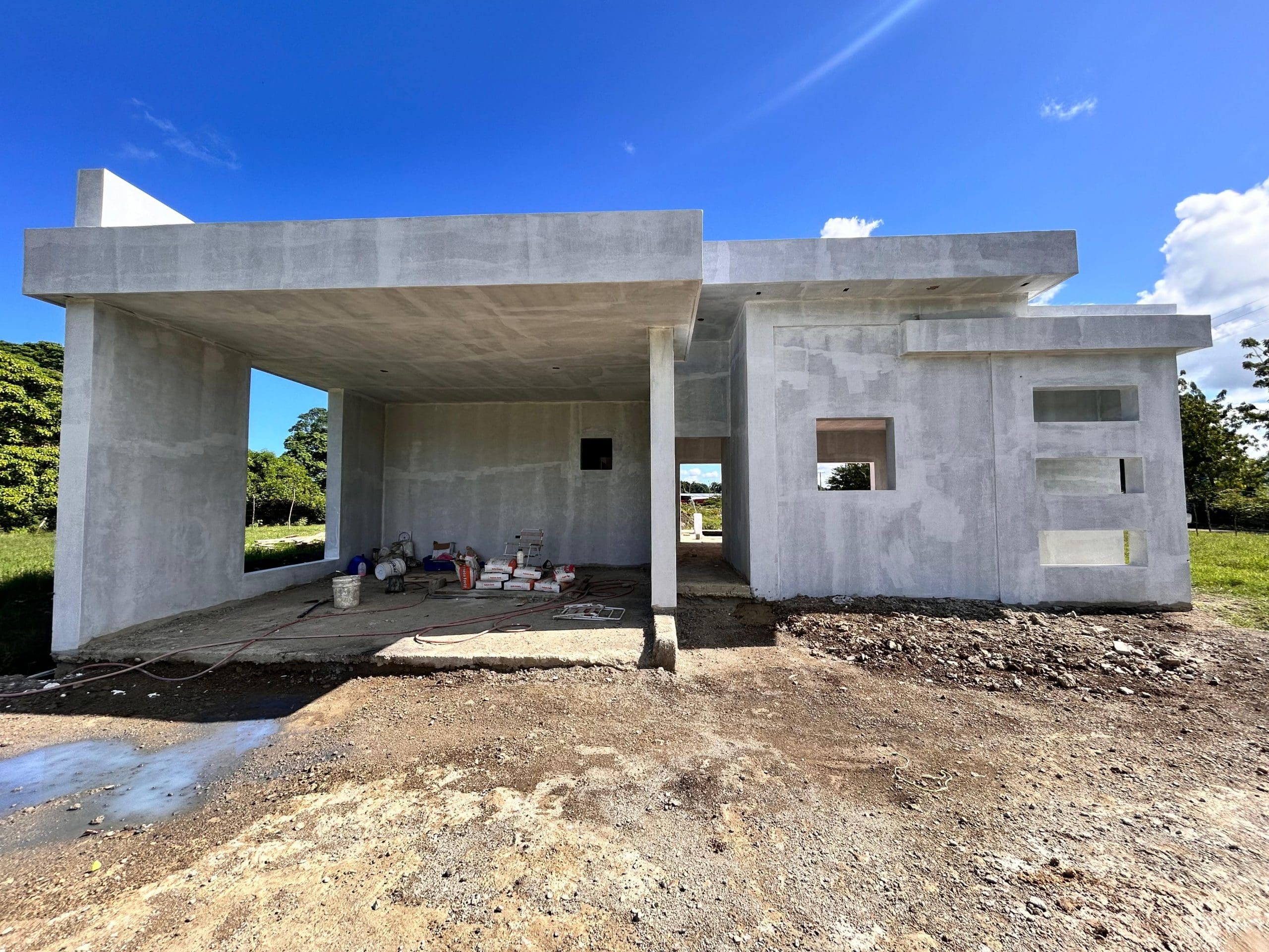 buyDRproperty Unfinished modern house construction with concrete walls and window openings under a bright blue sky. Sosua Real Estate
