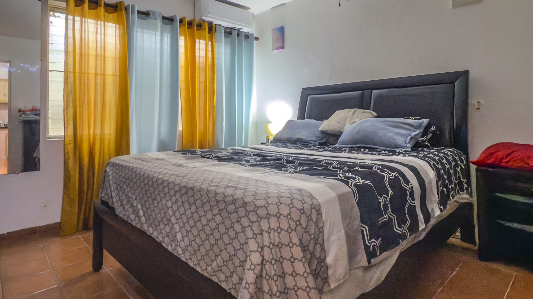 buyDRproperty Bedroom with a bed, yellow and blue curtains, and tile floor in Sosúa, near the playa. Sosua Real Estate