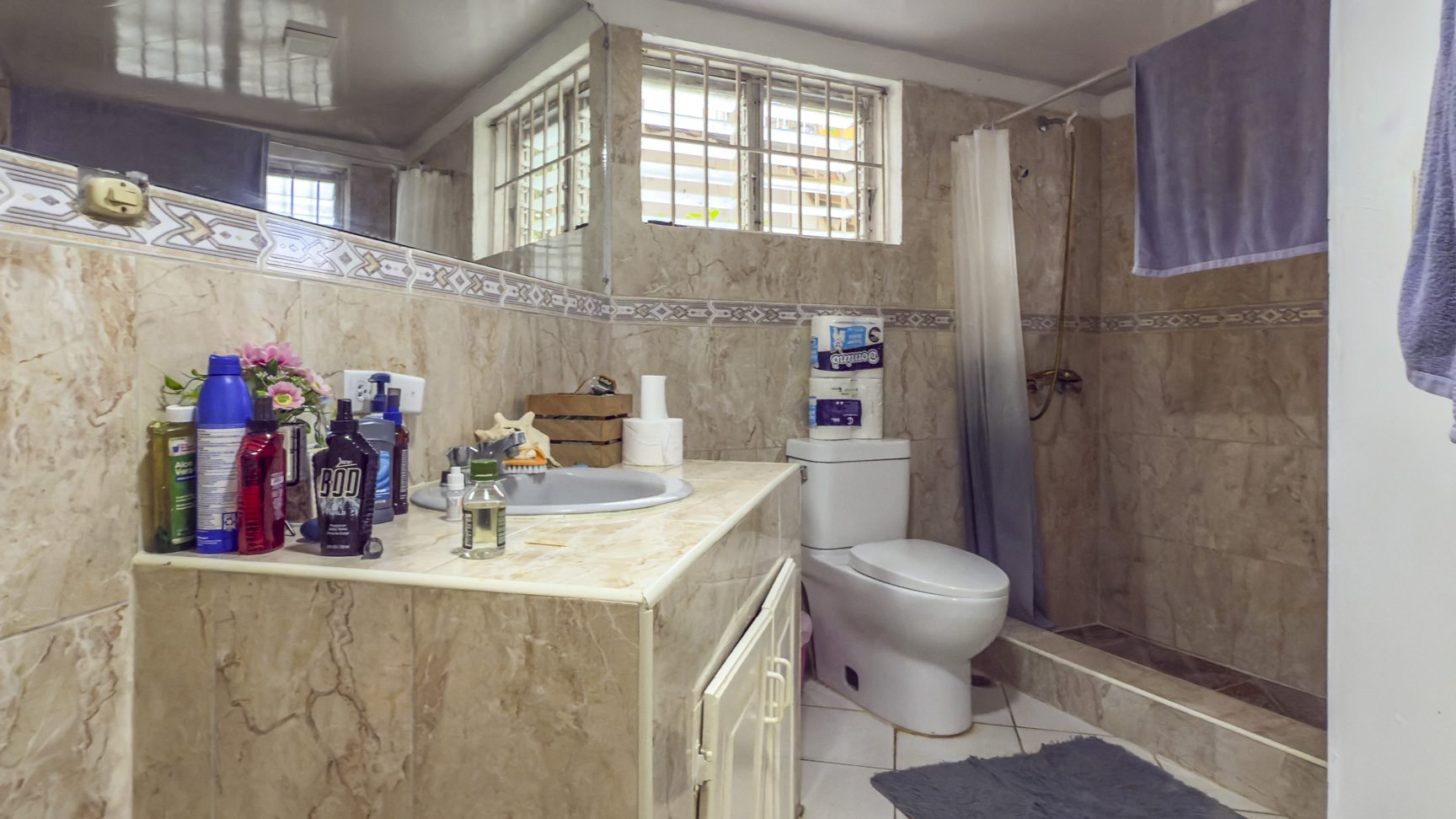 buyDRproperty Bathroom with beige tile, toilet, sink, and window in Sosúa. Near the playa! Sosua Real Estate