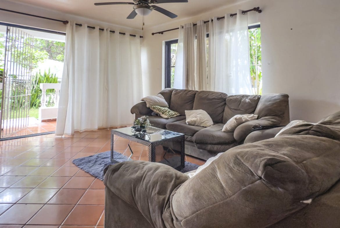 buyDRproperty Living room with brown couches, tile floor, and patio doors leading to a Sosúa playa view. Sosua Real Estate
