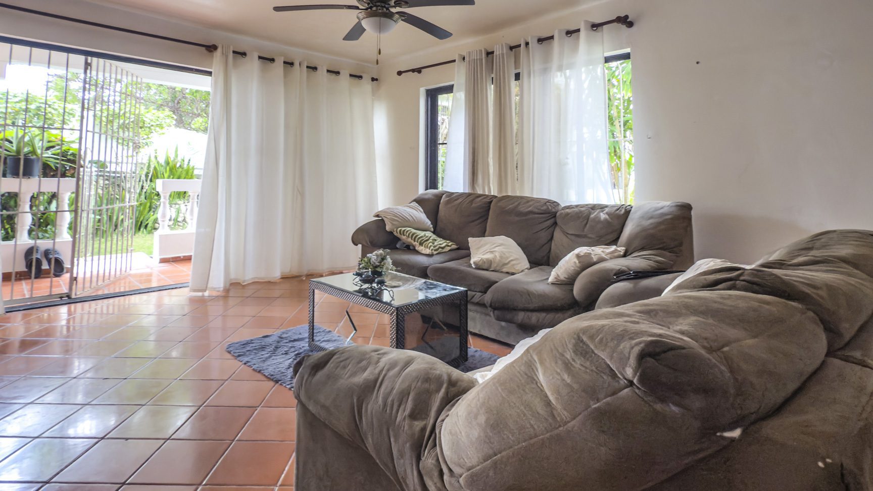 buyDRproperty Living room with brown couches, tile floor, and patio doors leading to a Sosúa playa view. Sosua Real Estate