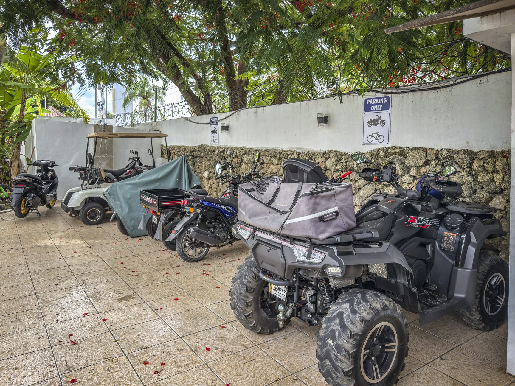 buyDRproperty ATV, motorcycles, and golf cart parked in a designated area with a "Parking Only" sign in Sosúa near playa. Sosua Real Estate