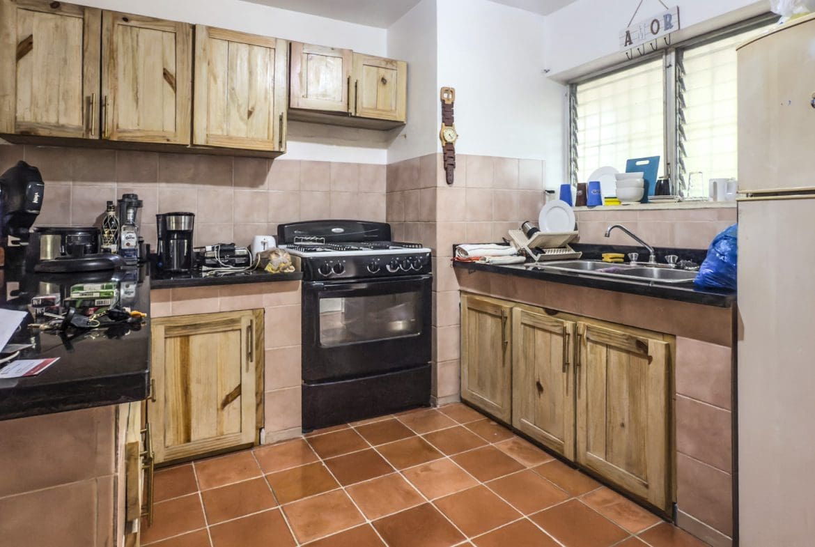 buyDRproperty Kitchen with wood cabinets, black countertops, oven, and tile floor near playa. Sosua Real Estate