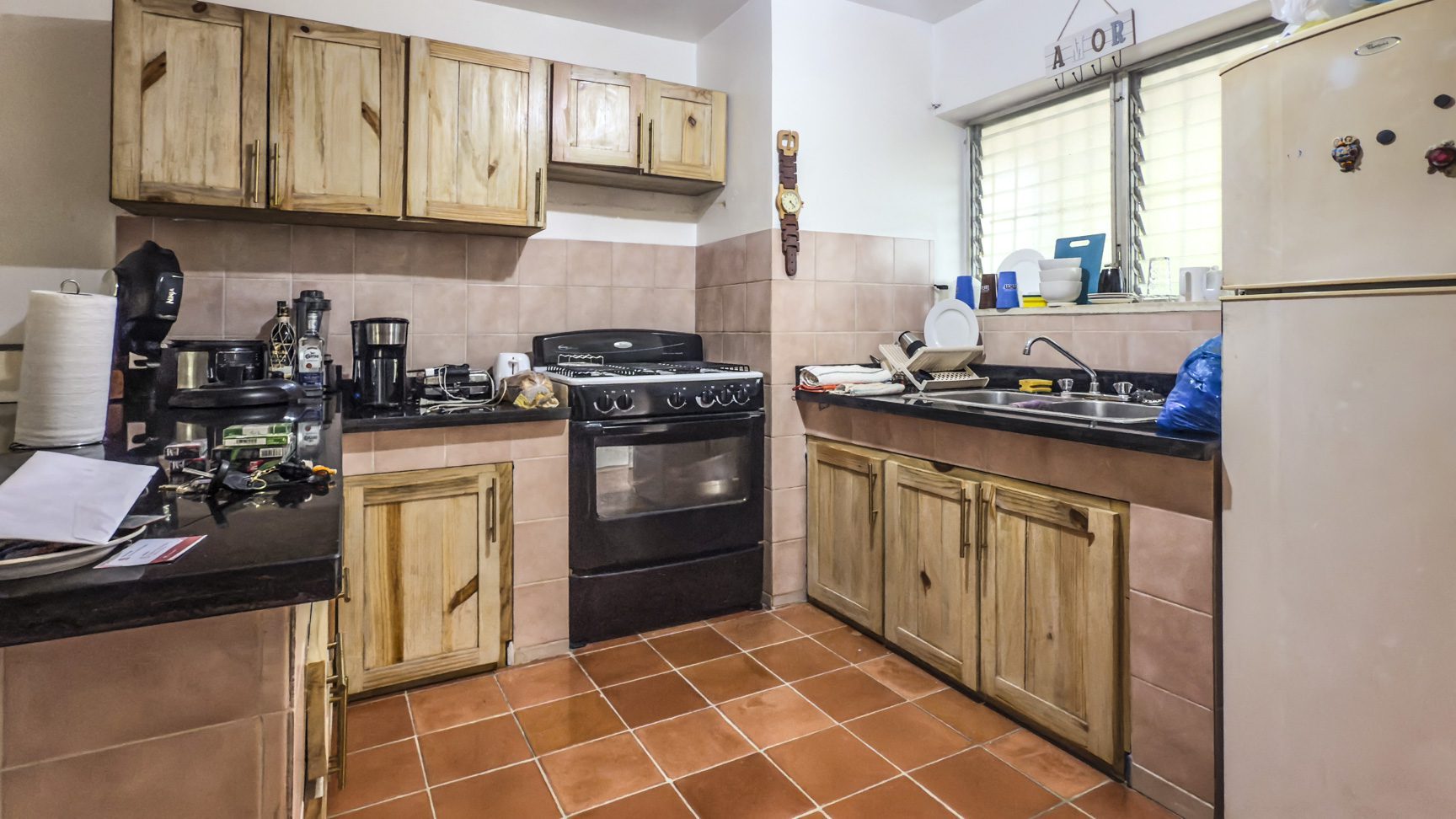 buyDRproperty Kitchen with wood cabinets, black countertops, oven, and tile floor near playa. Sosua Real Estate