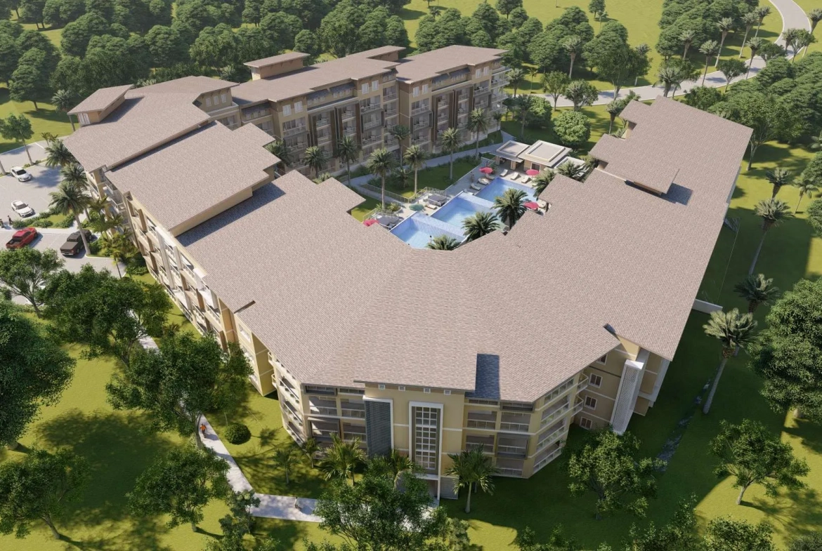 buyDRproperty Aerial view of a luxury resort with a central pool, surrounded by lush green trees and parking. Sosua Real Estate