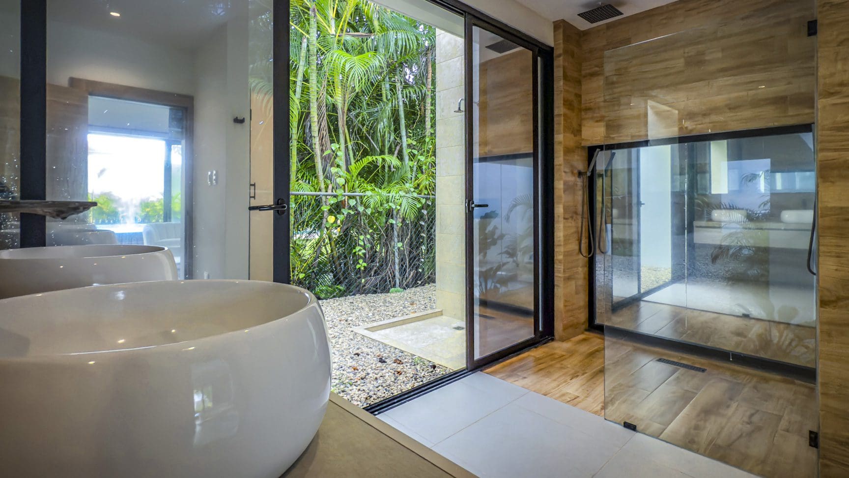 buyDRproperty Luxury bathroom with tub, open shower, and tropical garden view. Sosua Real Estate