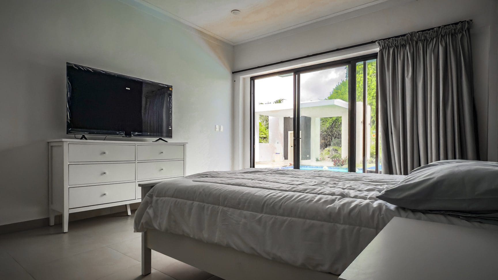 buyDRproperty Luxury bedroom with TV and sliding glass doors to a pool at Sosua Ocean Village. Sosua Real Estate