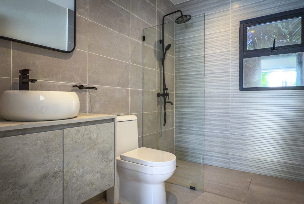 buyDRproperty Modern bathroom with walk-in shower, toilet, and sink in a luxury villa. Sosua Real Estate