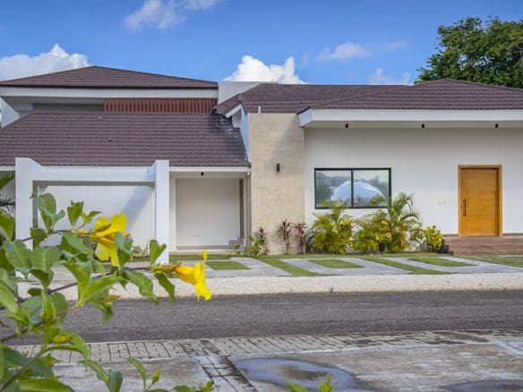 buyDRproperty Modern luxury villa with a brown roof and white exterior, palm trees, and blue sky. Sosua Real Estate
