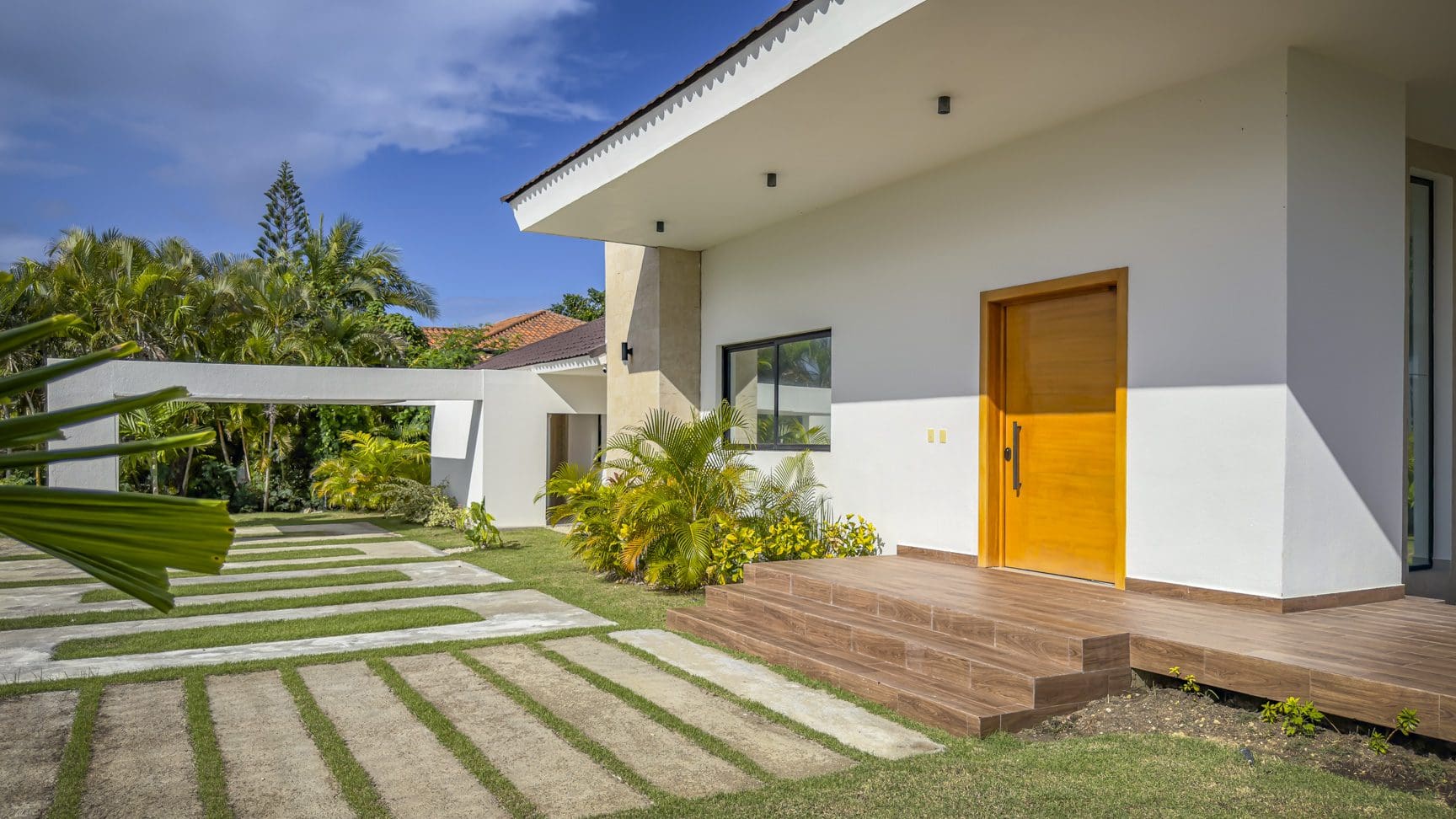 buyDRproperty Modern luxury villa entrance with wooden door and walkway in Sosua Ocean Village. Sosua Real Estate