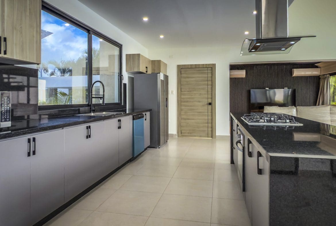 buyDRproperty Modern kitchen in a luxury Sosua Ocean Village villa, with black countertops and stainless steel appliances. Sosua Real Estate
