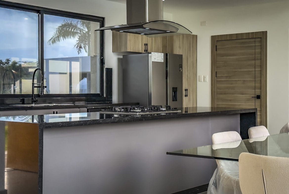 buyDRproperty Modern kitchen in a luxury villa with stainless steel appliances and a dark countertop. Sosua Real Estate