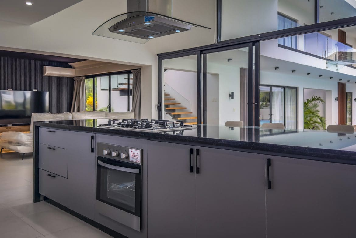buyDRproperty Luxury villa kitchen with black countertops and stainless steel appliances in Sosua Ocean Village. Sosua Real Estate