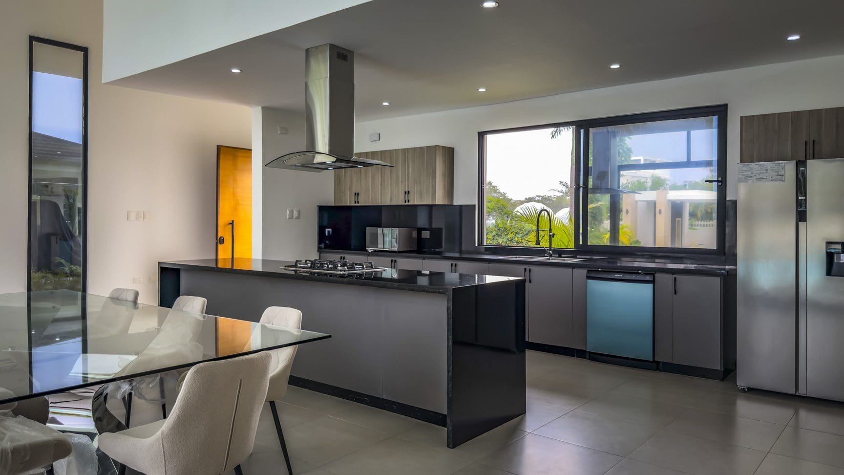 buyDRproperty Modern kitchen in a luxury villa with island, stainless steel appliances, and large window. Sosua Real Estate