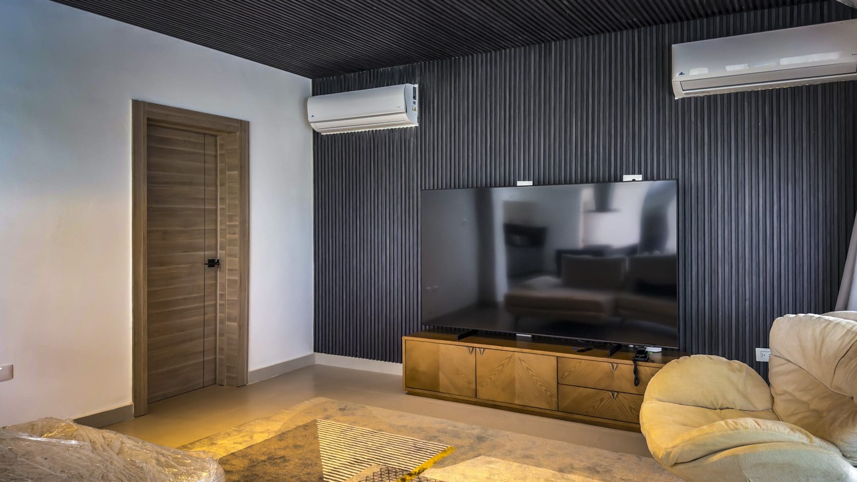 buyDRproperty Luxury villa interior with TV, modern wall paneling, and neutral tones in Sosua Ocean Village. Sosua Real Estate