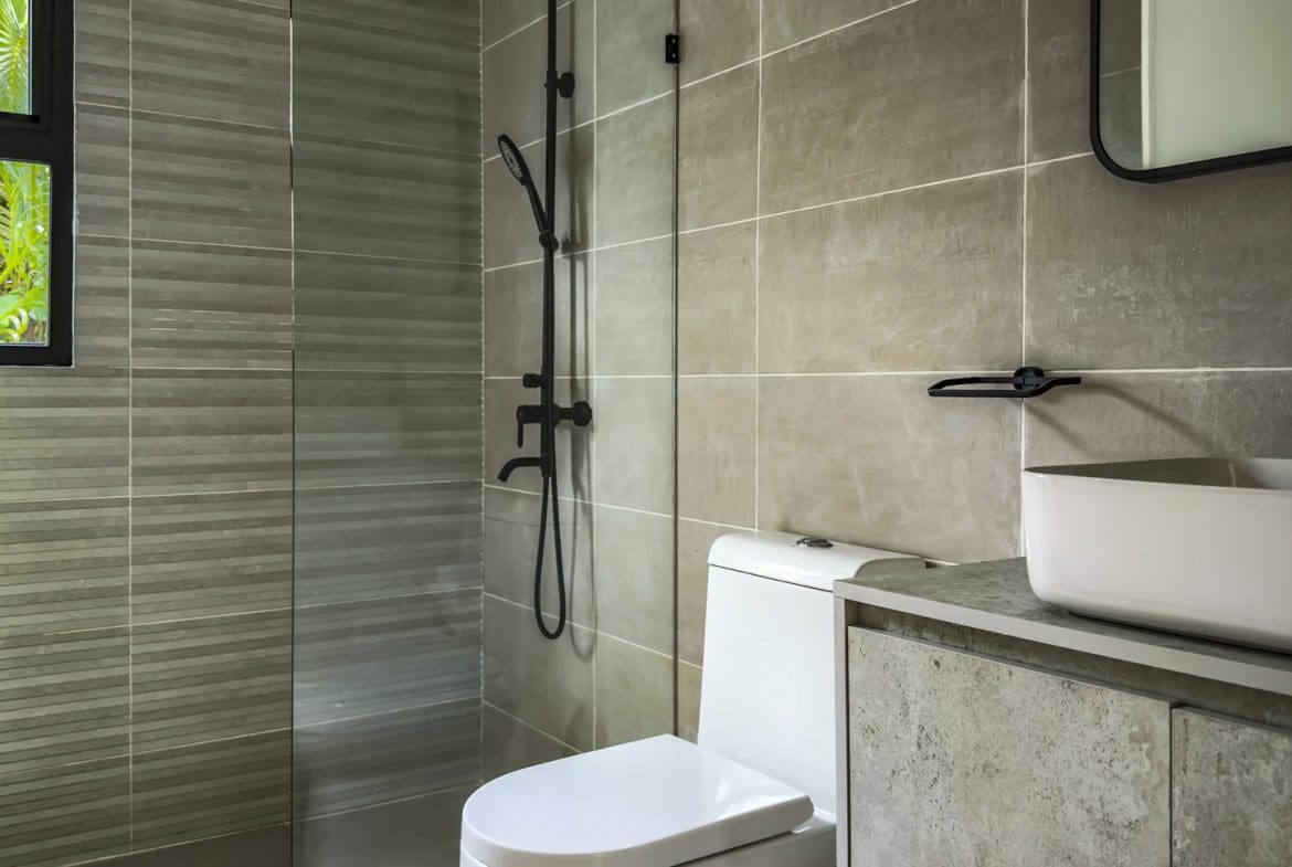 buyDRproperty Modern bathroom in a luxury villa with gray tile, a toilet, and a sink. Sosua Real Estate