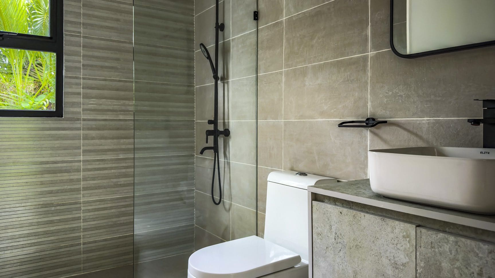 buyDRproperty Modern bathroom in a luxury villa with gray tile, a toilet, and a sink. Sosua Real Estate