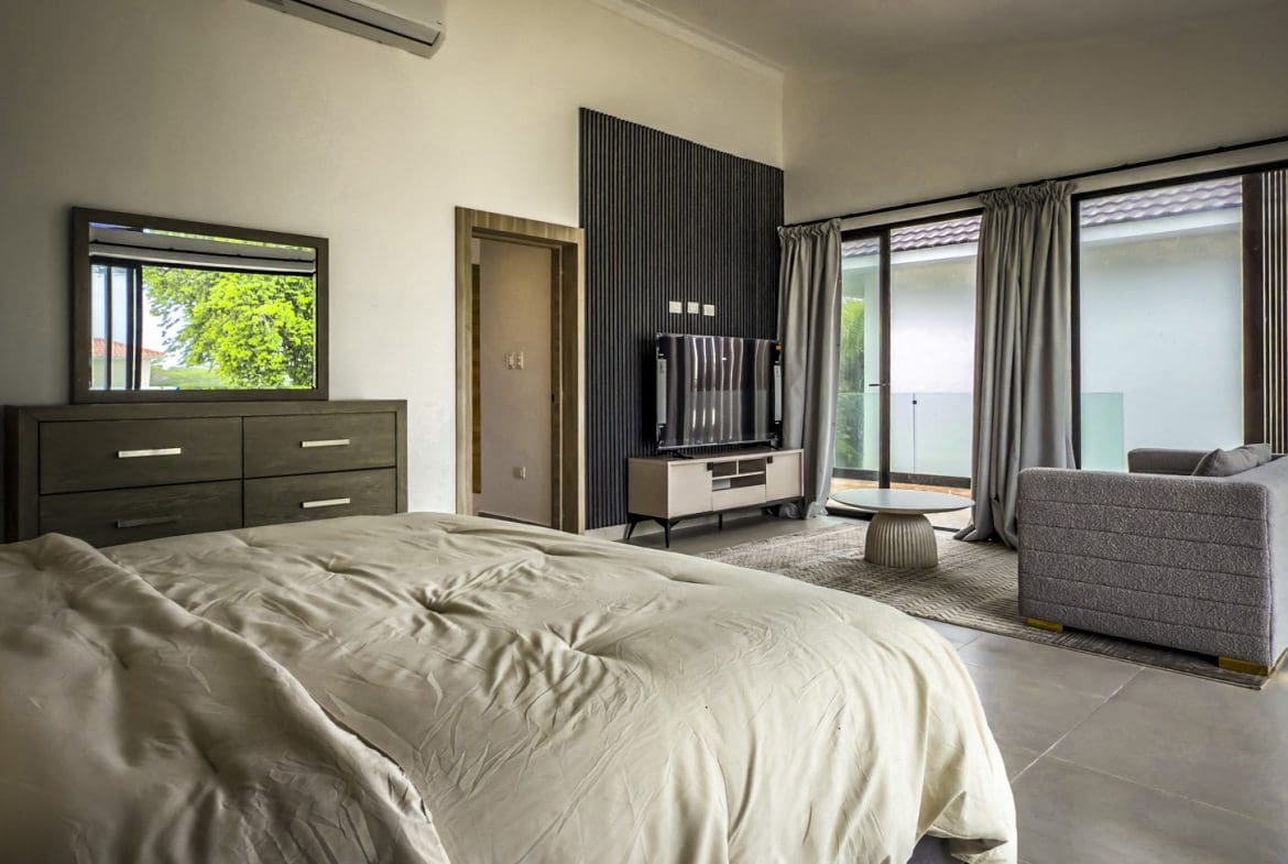 buyDRproperty Luxury villa bedroom with bed, TV, and seating area in Sosua Ocean Village. Sosua Real Estate